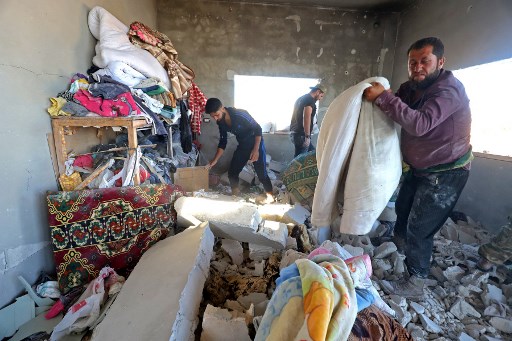Des Syriens tentent de récupérer des biens dans une maison gravement endommagée par des tirs d'artillerie dans le village de Kansafra, dans la campagne du sud de la province syrienne d'Idleb. (Abdulaziz KETAZ/AFP)