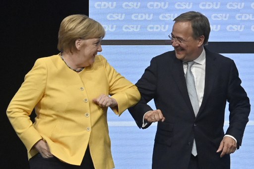 Le chef du parti conservateur de l'Union chrétienne-démocrate (CDU) et candidat à la chancellerie aux prochaines élections générales, Armin Laschet (à droite), cogne la chancelière allemande Angela Merkel à la fin d'un rassemblement de campagne CDU/CSU pour les élections générales prévues le 26 septembre 2021, au Berliner Tempodrom à Berlin le 21 août 2021. (John MacDougall/AFP)