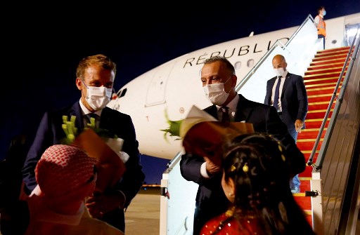 Le président français Emmanuel Macron (à gauche) accueilli par des enfants alors qu'il est reçu par le Premier ministre irakien Mustafa al-Kazimi après son arrivée à l'aéroport de Bagdad avant un sommet régional le 28 août 2021. (Bureau de presse du Premier ministre irakien/ AFP)