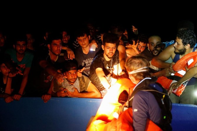 Un membre de l'équipage du navire de sauvetage des migrants de l'ONG allemande Sea-Watch 3 distribue des gilets de sauvetage aux migrants sur un bateau en bois surpeuplé. (Photo, Reuters)