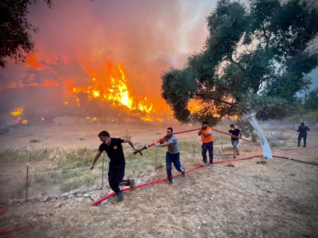 Des pompiers et des volontaires locaux portent des tuyaux d'arrosage alors qu'ils se battent pour éteindre un incendie de forêt à Oren, dans la région de Mugla, le 6 août 2021 alors que la Turquie lutte contre ses incendies de forêt les plus meurtriers depuis des décennies. (AFP)