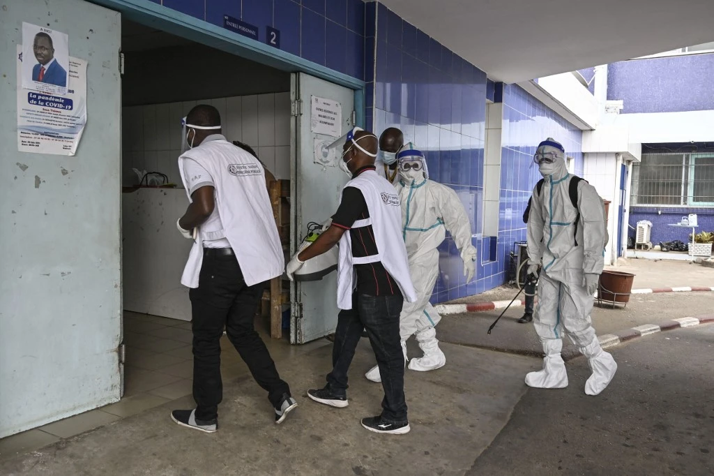 Deux agents de l'Institut National d'Hygiène Publique (INHP) portant des combinaisons d'équipements de protection individuelle (EPI) contre le virus Ebola arrivent au CHU de Cocody pour une opération de désinfection des locaux après le passage d'un premier patient Ebola, à Cocody en août 16 août 2021. (AFP)