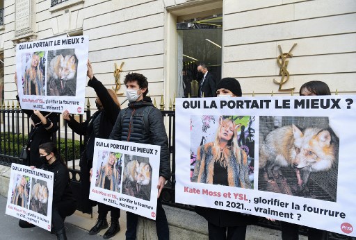 Des militants de l'association PETA brandissent des affiches devant un magasin Yves Saint-Laurent pour appeler la marque à cesser de glorifier la fourrure à Paris le 10 mars 2021. (Alain Jocard / AFP)