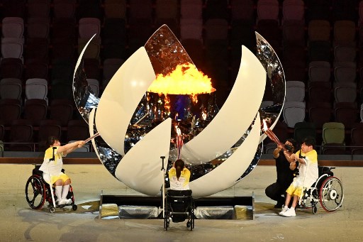 Trois porteurs de flambeau illuminent la vasque paralympique lors de la cérémonie d'ouverture des Jeux paralympiques de Tokyo 2020 au stade olympique de Tokyo le 24 août 2021. (Charly Triballeau/AFP)