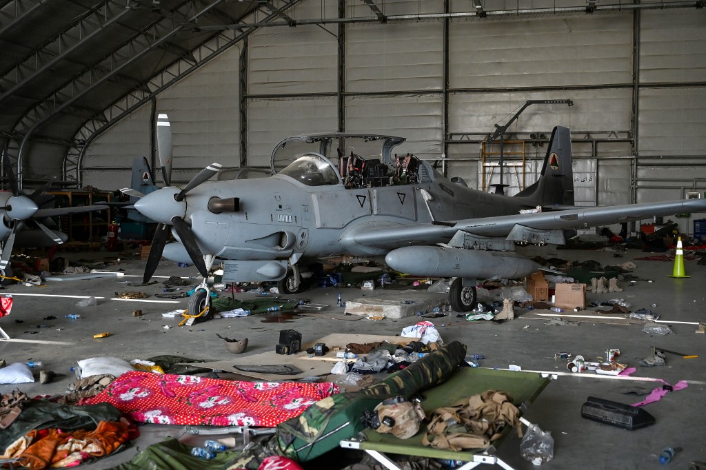 Un avion de chasse à hélice Embraer "Super Tucano" mis hors d'usage, gisant dans un hangar de l'aéroport de Kaboul devant des débris d'articles divers, comme des gilets pare balles et des centaines de munitions. (Photo, AFP)