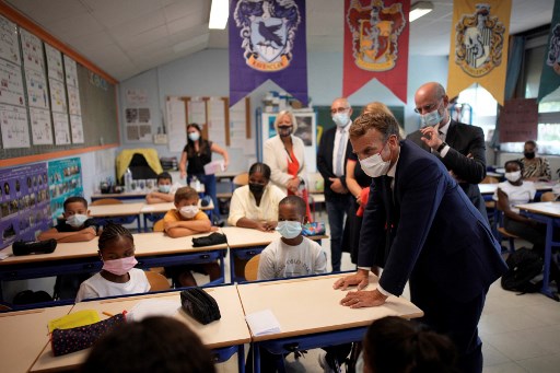 Le président français Emmanuel Macron (à droite) accompagné du ministre français de l'Éducation, de la Jeunesse et des Sports Jean-Michel Blanquer (2e à droite) s'entretient avec les enfants lors de sa visite à l'école primaire de Bouge pour la rentrée le 2 septembre 2021 à Marseille, sud de la France. (Daniel Cole/Pool/AFP)
