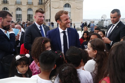 Le président français Emmanuel Macron (au centre) s'entretient avec des enfants après avoir prononcé un discours au Palais du Pharo, le 2 septembre 2021, dans le cadre d'une visite de trois jours à Marseille, dans le sud de la France. (Guillaume Horcajuelo / Pool / AFP)