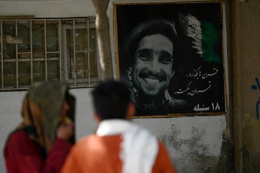 Passants, devant une affiche du défunt commandant afghan Ahmad Shah Massoud à Kaboul le 8 septembre 2021. Vingt ans plus tard, l'assassinat de Massoud et les attaques du 11 septembre contre les États-Unis sont pour de nombreux Afghans les deux cataclysmes qui ont déclenché une nouvelle ère d'incertitude et d'effusion de sang. (Aamir Qureishi/AFP)