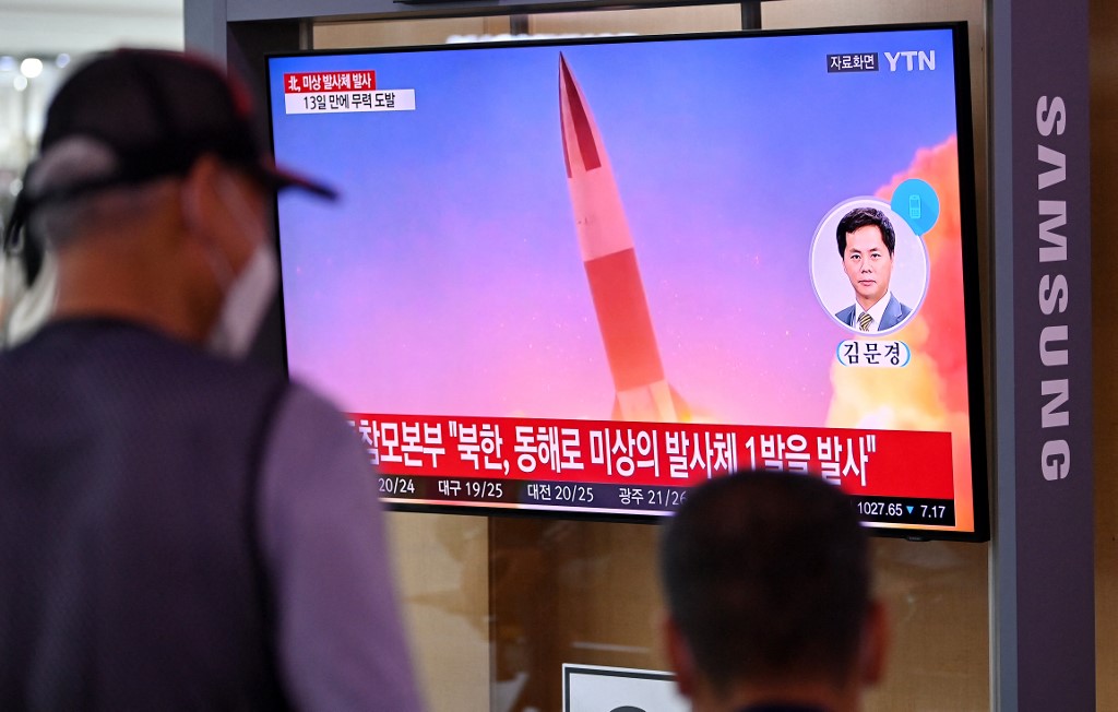 Des personnes regardent une émission télévisée montrant des images d'archives d'un essai de missile nord-coréen, dans une gare de Séoul le 28 septembre 2021 (AFP)