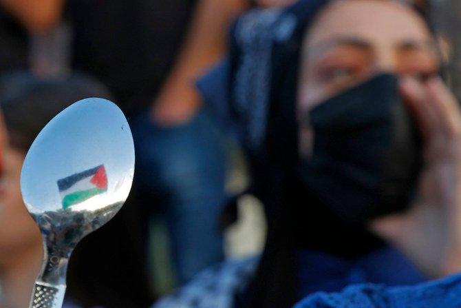 Des manifestants arabes israéliens brandissent des cuillères, outils que six prisonniers palestiniens auraient utilisé pour s'évader de la prison israélienne de Gilboa. (AFP)