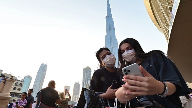 Des femmes portant des masques de protection regardent un téléphone portable devant Burj Khalifa, à Dubaï, le 8 mars 2020 (Photo, AFP)