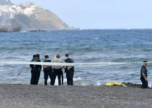 Des membres de la Guardia Civil espagnole se tiennent à côté du corps d'un migrant sur la plage de l'enclave espagnole de Ceuta, le 20 mai 2021 (Photo, AFP)