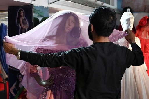 Un commerçant arrange une robe de mariée sur un mannequin dans un magasin de vêtements pour femmes à Kaboul le 2 septembre 2021. (Aamir Qureshi/AFP)
