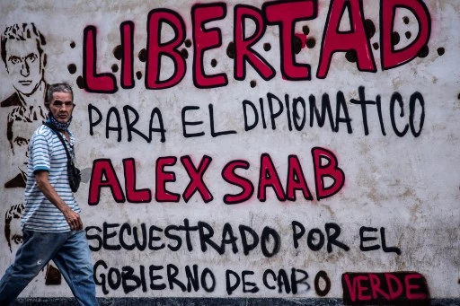 Dans cette photo d'archives prise le 23 février 2021, un homme passe devant un graffiti indiquant "Liberté pour le diplomate Alex Saab, kidnappé par le gouvernement du Cap-Vert" à Caracas. (Youri Cortez/AFP)