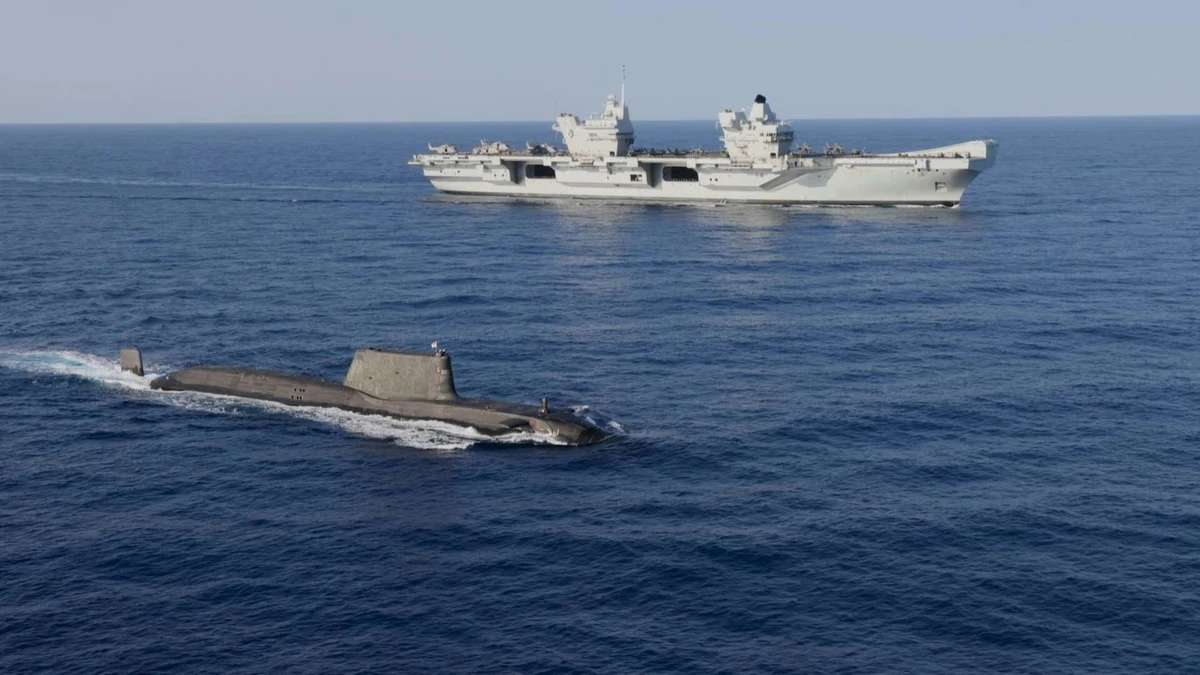 Travelling Sous-marin de la classe Astute en surface avec le porte-avion HMS Queen Elizabeth en arrière-plan (Photo, AFP)