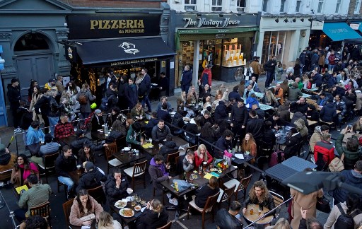 Des gens assis à des tables à l'extérieur pour manger et boire dans des bars et restaurants rouverts, dans la rue du quartier de Soho à Londres, le 16 avril 2021, à la suite de la deuxième étape de la feuille de route du gouvernement sur le troisième verrouillage national de l'Angleterre. (Niklas Halle'n/AFP)