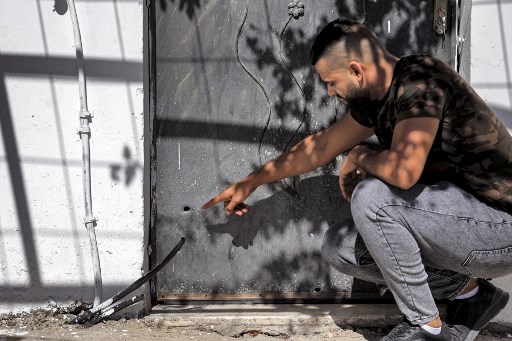 Un homme montre des traces de balles dans une porte à la suite d'une opération israélienne visant à capturer les deux derniers des six prisonniers palestiniens qui avaient creusé un tunnel hors de la prison israélienne de haute sécurité de Gilboa, et qui se réfugiaient dans une maison palestinienne à Jénine dans le nord de la Cisjordanie occupée, le 19 septembre 2021. (Jaafar Ashtiyeh/AFP)