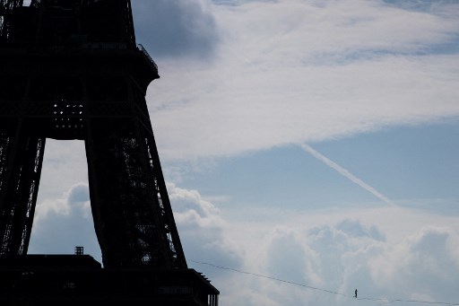 Le highliner français Nathan Paulin sur une slackline de 70 mètres de haut et 670 mètres entre la Tour Eiffel et le Théâtre National de Chaillot, le 19 septembre 2021. (Sameer Al-Doumy/AFP)