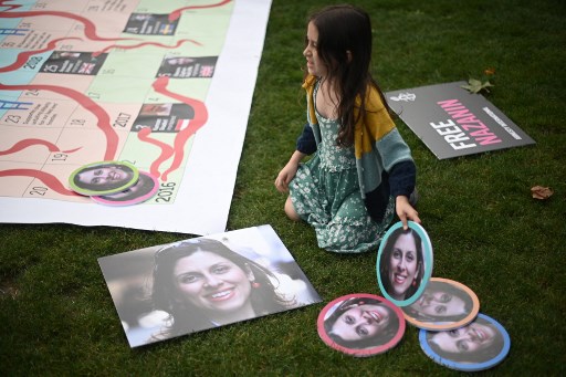Gabriella Ratcliffe, fille de Nazanin Zaghari-Ratcliffe, une travailleuse humanitaire britannique emprisonnée en Iran, place des portraits de sa mère sur un panneau géant de serpents et d'échelles sur la place du Parlement, à Londres, pour marquer le 2 000e jour de sa détention en Iran le 23 septembre 2021.(Daniel Leal-Olivas/AFP)