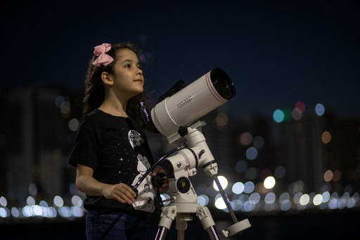 L'astronome brésilienne Nicole Oliveira, âgée de 8 ans, pose pour une photo avec son télescope à Fortaleza, au Brésil, le 21 septembre 2021. (Jarbas Oliveira / AFP)