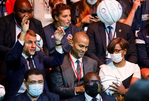 Le président français Emmanuel Macron (à gauche) lance un ballon à côté de l'ancien basketteur franco-américain Tony Parker (au centre) et de la jeune ministre française de l'Égalité des genres Elisabeth Moreno (à droite) alors qu'il assiste à un match de basket-ball lors d'un sommet Afrique-France 2021 à Montpellier, dans le sud de la France, le 8 octobre 2021.(Ludovic Marin/AFP)