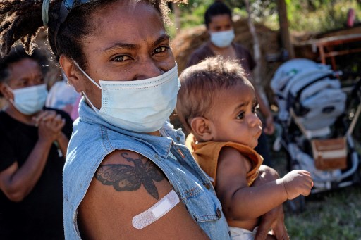 Samantha Paouro, 35 ans, de la tribu Kouma, tient un bébé dans ses bras après avoir reçu une dose du vaccin Pfizer/BioNTech Covid-19 lors d'une campagne de vaccination contre le Covid-19 pour la tribu Kouma, en Nouvelle-Calédonie, le 11 octobre 2021.(Théo Rouby/AFP)