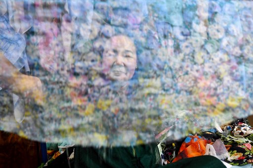 L’artiste Tran Thanh Thuc regarde à travers un morceau de tissu transformé en œuvre d’art dans son home studio à Hanoi. (Nhac Nguyen / AFP)