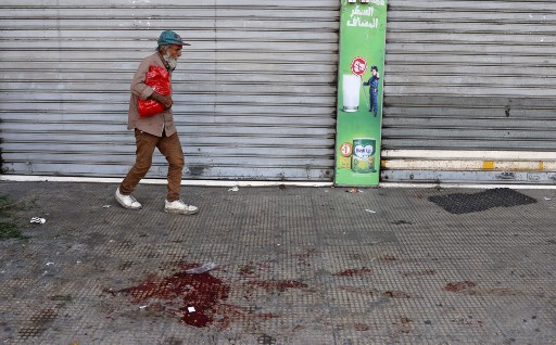 Un homme passe devant une trace de sang dans le quartier de Tayouneh, dans la banlieue sud de la capitale Beyrouth le 14 octobre 2021, lors d'affrontements suite à une manifestation de partisans du Hezbollah et du mouvement Amal. (Joseph Eid/AFP)