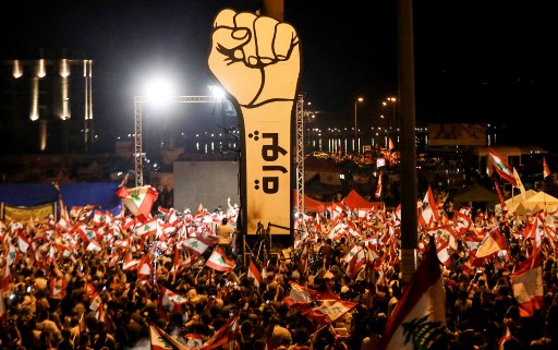 Dans cette photo d'archive prise le 10 novembre 2019, des manifestants libanais brandissent des drapeaux nationaux lors des manifestations antigouvernementales en cours au cœur de Beyrouth. Deux ans après qu'un mouvement de protestation aujourd'hui disparu a secoué le Liban, les militants de l'opposition espèrent que les sondages parlementaires remettront en cause la mainmise de l'élite dirigeante sur le pays. (Anwar Amro / AFP)