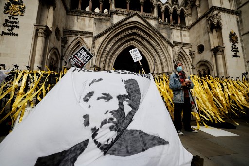 Des manifestants affichent une banderole avec une image du fondateur de WikiLeaks, Julian Assange, lors d'une manifestation devant la Cour royale de justice de Londres le 28 octobre 2021, le deuxième jour d'une audience d'appel du gouvernement américain contre le refus du Royaume-Uni d'extrader Assange. (Tolga Akmen / AFP)
