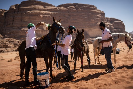 La princesse Jalila Bint Ali de Jordanie (au centre) prend soin de son cheval lors de la première étape des « Gallops of Jordan » le 25 octobre 2021 au désert du Wadi Rum, à 300 kilomètres au sud d'Amman, le 26 octobre 2021. (Lionel Bonaventure/AFP)