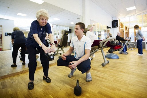 L'entraîneur suédois Kristoffer Sjoeberg (à droite), veille sur Margareta Nordin, 92 ans, lors de son cours hebdomadaire avec un groupe de retraités suédois, au club de santé Sickla Haelsocenter à la périphérie de Stockholm le 11 novembre 2011. (Jonathan Nackstrand /AFP)