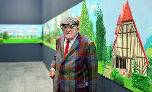 Le peintre britannique David Hockney au musée de l'Orangerie à Paris, le 7 octobre 2021, devant son tableau «Un an en Normandie», une œuvre de 91 mètres de long peinte pendant le confinement en 2020. Hockney a réalisé une centaine de dessins sur iPad en quelques semaines et a capturé les effets de la lumière et du changement climatique au cours des quatre saisons. (Thomas Coex/AFP)
