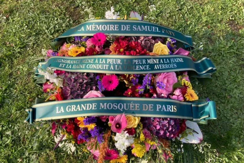 Une gerbe de fleurs devant le collège du Bois de l’Aune, où le professeur enseignait portant une citation du philosophe musulman Ibn Roshd, plus connu en Occident sous le nom d’«Averroès»:«L’ignorance mène à la peur. La peur mène à la haine et la haine conduit à la violence.» (Photo, Grande Mosquée de Paris)
