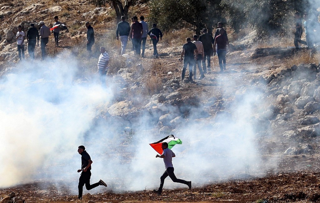 Des manifestants palestiniens fuient les gaz lacrymogènes tirés par les forces de sécurité israéliennes à Beit Dajan, à l'est de Naplouse en Cisjordanie occupée, le 5 novembre 2021. (AFP)