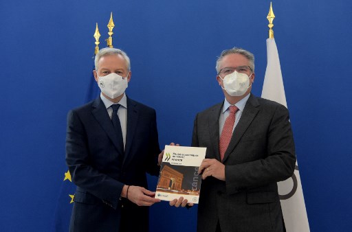 Le ministre français de l'Économie et des Finances Bruno Le Maire (à gauche) et le président de l'OCDE Mathias Cormann (à droite) montrent une nouvelle étude économique de l'OCDE sur la France avant une conférence de presse au ministère de l'Économie à Paris, le 18 novembre 2021. (Eric Piermont/AFP)
