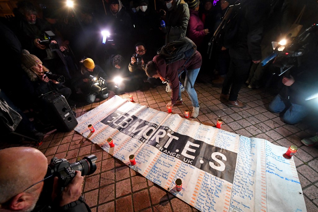 Des membres d'associations d'aide aux migrants se rassemblent à côté d'une pancarte indiquant le nombre de morts (303) et les noms des disparus, place Richelieu à Calais, le 25 novembre 2021. Au moins 27 migrants sont morts le 24 novembre en traversant la France vers l'Angleterre lorsque leur bateau a coulé au large du port de Calais, ont déclaré les autorités françaises, la catastrophe la plus meurtrière depuis que la Manche est devenue une partie importante de la route des migrants. FRANCOIS LO PRESTI / AFP