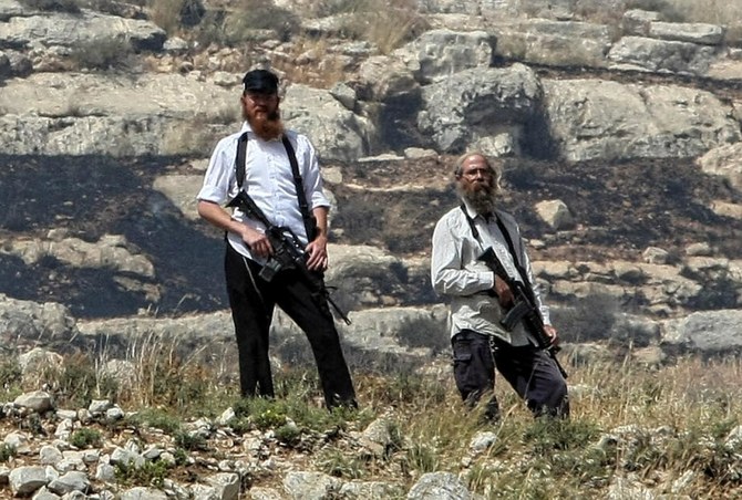 Des colons armés de la colonie juive radicale d'Yitzhar patrouillent au bord d'une falaise qui surplombe un village palestinien. (AFP)