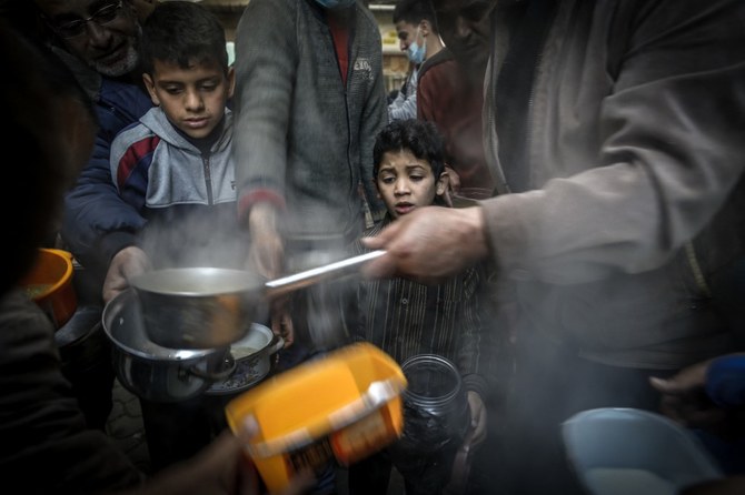 Un garçon attend pendant que le Palestinien Walid al-Hattab (à droite) distribue de la soupe aux personnes dans le besoin pendant le mois du Ramadan dans la ville de Gaza, durant la pandémie de Covid-19. (Photo, AFP)