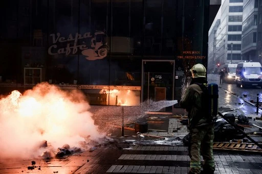 Un pompier belge s'emploie à éteindre un incendie lors d'une manifestation contre les mesures Covid-19, dont le pass sanitaire du pays, à Bruxelles le 21 novembre 2021. (Kenzo Tribouillard/AFP)
