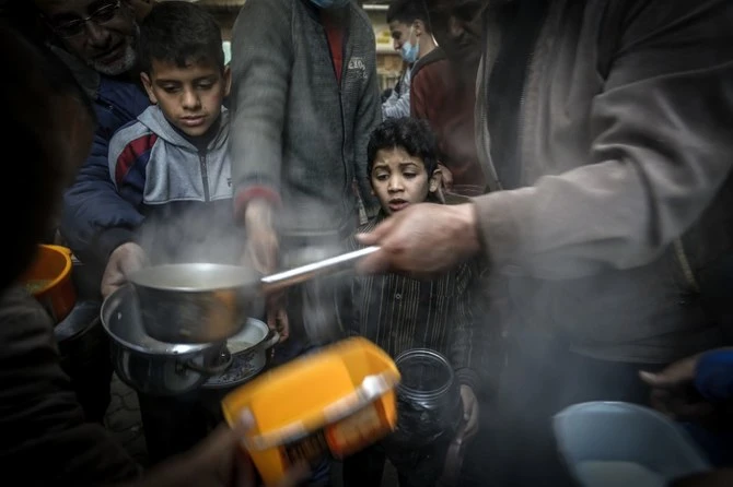 Un garçon attend pendant que le Palestinien Walid al-Hattab (à droite) distribue de la soupe aux personnes dans le besoin pendant le mois du Ramadan dans la ville de Gaza, durant la pandémie de Covid-19. (Photo, AFP)