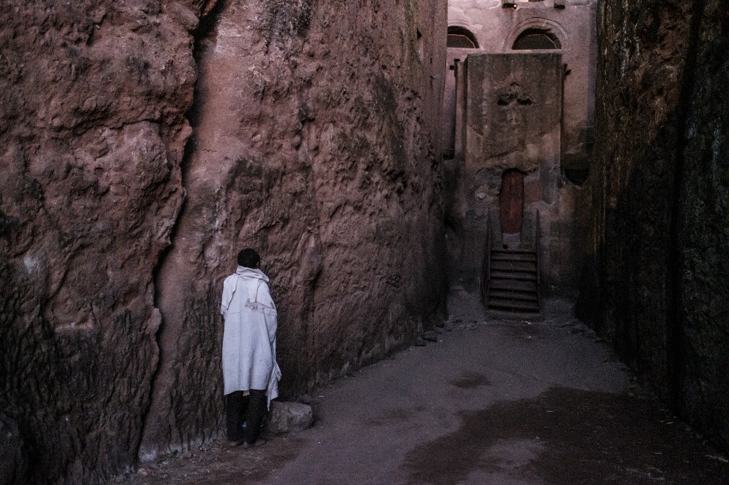 Un pèlerin prie à l'entrée de l'une des églises creusées dans le roc avant le Noël orthodoxe éthiopien à Lalibela, en Éthiopie, le 5 janvier 2019. Les onze églises creusées dans le roc sont l'un des sites du patrimoine mondial de l'UNESCO en Éthiopie. (AFP)