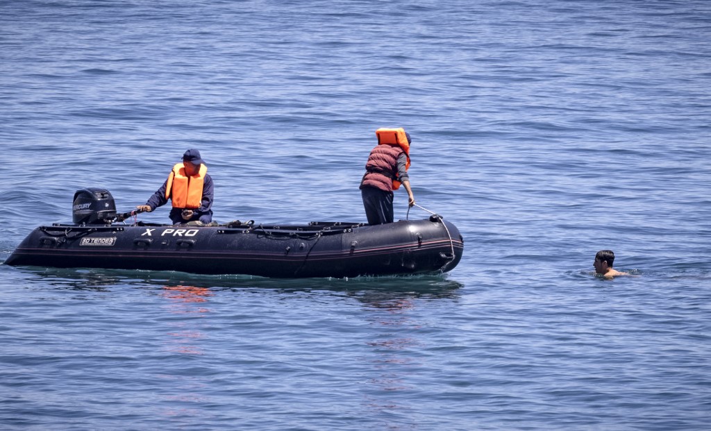 Des officiers de la Marine royale marocaine interceptent des migrants dans l'eau à la frontière entre le Maroc et l'enclave espagnole de Ceuta le 19 mai 2021 à Fnideq. (AFP)
