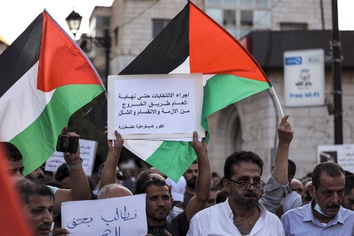 Des pancartes sont brandies pour les élections palestiniennes qui auront lieu avant la fin de l'année alors que des manifestants se rassemblent dans la ville de Ramallah en Cisjordanie occupée le 25 août 2021 pour une manifestation dénonçant l'Autorité palestinienne à la suite de la mort du militant Nizar Banat alors qu'il était sous la garde de ses forces de sécurité. (Abbas Momani / AFP)
