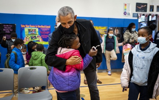 L'ancien président Barrack Obama serre une élève dans ses bras alors que des enfants se préparent à recevoir leur deuxième vaccin à l'école primaire Kimball à Washington, DC, le 30 novembre 2021. (Doug Mills/Pool/AFP)