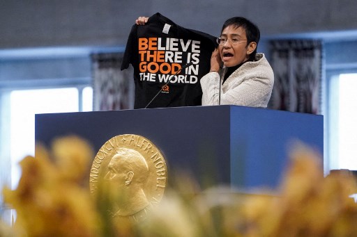 Lauréate du prix Nobel de la paix, la journaliste philippine Maria Ressa brandit un t-shirt avec l'inscription « Believe there is Good in the World » dans son discours lors de la cérémonie de remise du prix Nobel de la paix le 10 décembre 2021 à Oslo. (Stian Lysberg Solum / NTB / AFP)