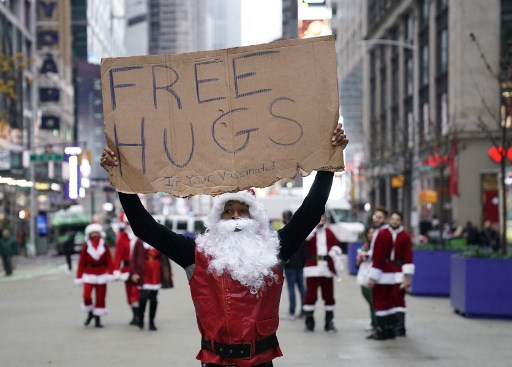 Dans cette photo d'archive prise le 11 décembre 2021, une personne déguisée en Père Noël offre des câlins gratuits (« si vous êtes vacciné » ) à la SantaCon 2021 à Times Square à New York. (Timothie A. Clary/AFP)