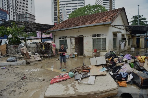 Un homme nettoie la boue de sa maison après qu'elle a été touchée par une inondation à Kuala Lumpur en Malaisie le 19 décembre 2021. (Arif Kartono / AFP)
