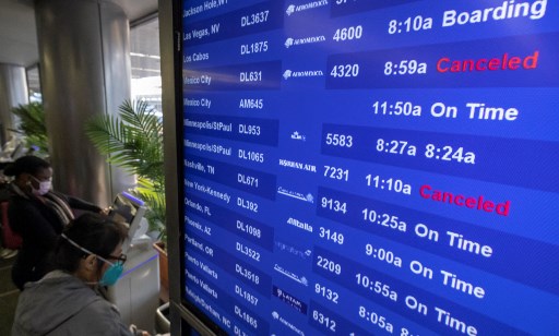 Les voyageurs vérifient les informations sur les vols à l'aéroport international de Los Angeles à Los Angeles, Californie, le 24 décembre 2021. Plus de 4500 vols ont été annulés et des milliers retardés dans le monde, car le variant hautement infectieux d'Omicron perturbe les voyages de vacances. (David Mcnew/AFP)