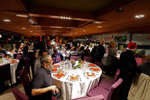 Les gens assistent à un « Secours Catholique-Caritas «, un groupe caritatif lié aux catholiques, à un dîner de réveillon de Noël sur un bateau fluvial le long de la Seine à Paris, la capitale française, le 24 décembre 2017. (Francois Guillot/AFP)